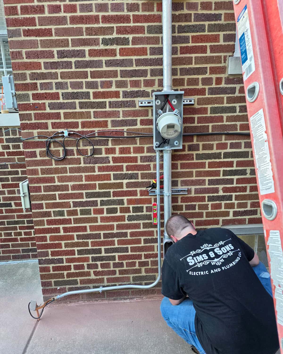 Electrician working on exterior residential electrical service equipment